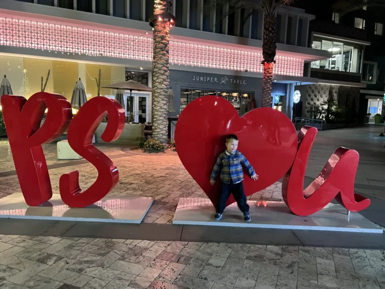 A little boy stands with a "PS loves u" sign