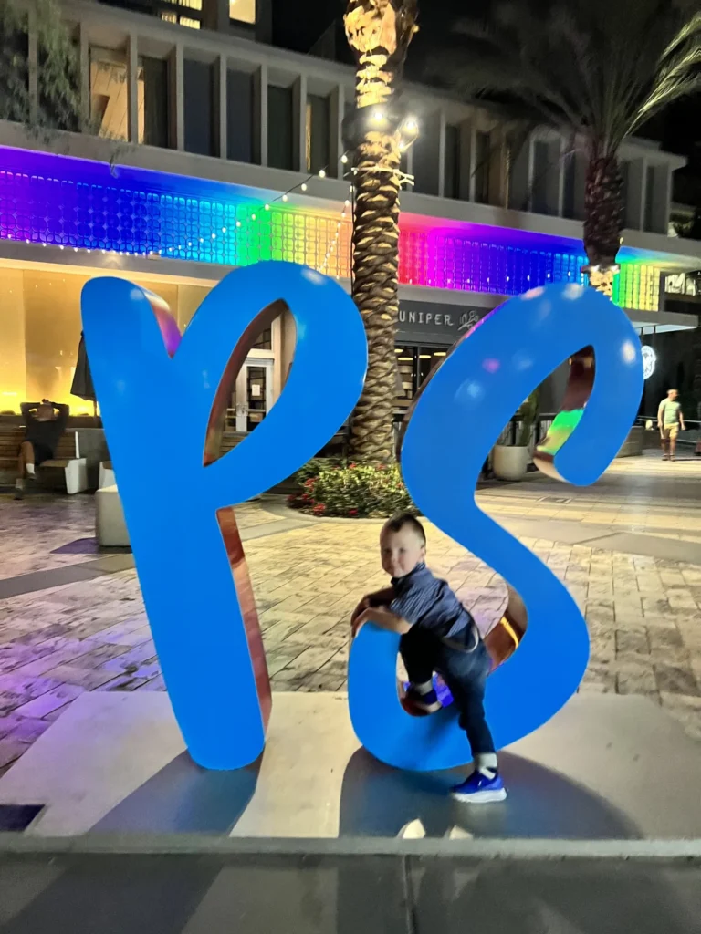 A kid sits on the Palm Springs sign