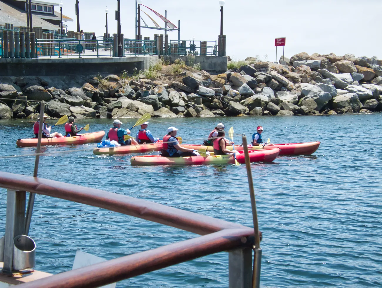A group of guests kayak with the jetty behidn them