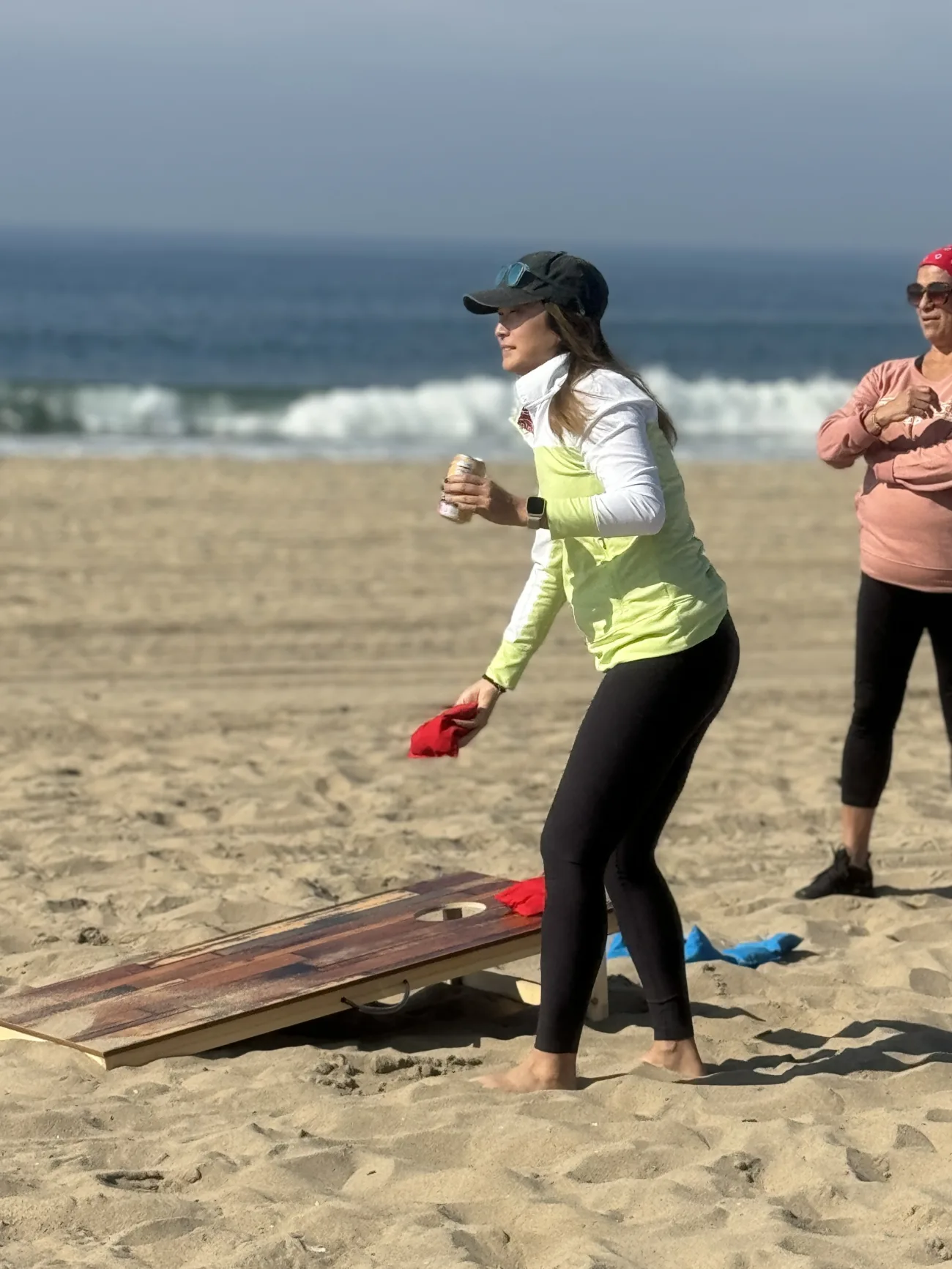 a woman tosses a bean bag during cornhole