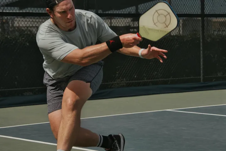 A man swings his pickleball raquet and hits