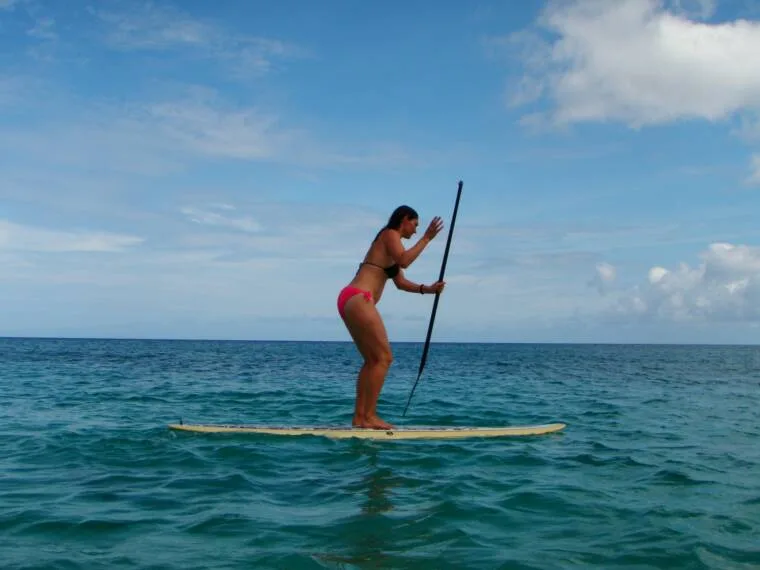 A girl paddles her paddleboard on the ocean