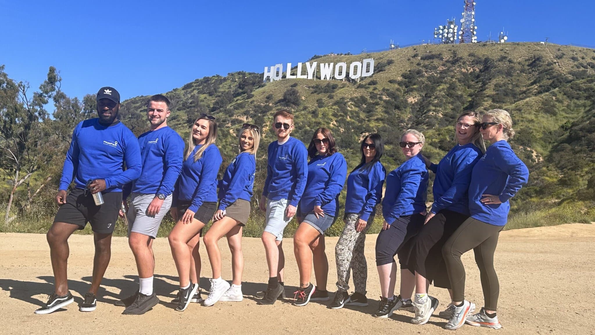 A group poses in front of the Hollywood Sign on the Hollywood Sign Tour