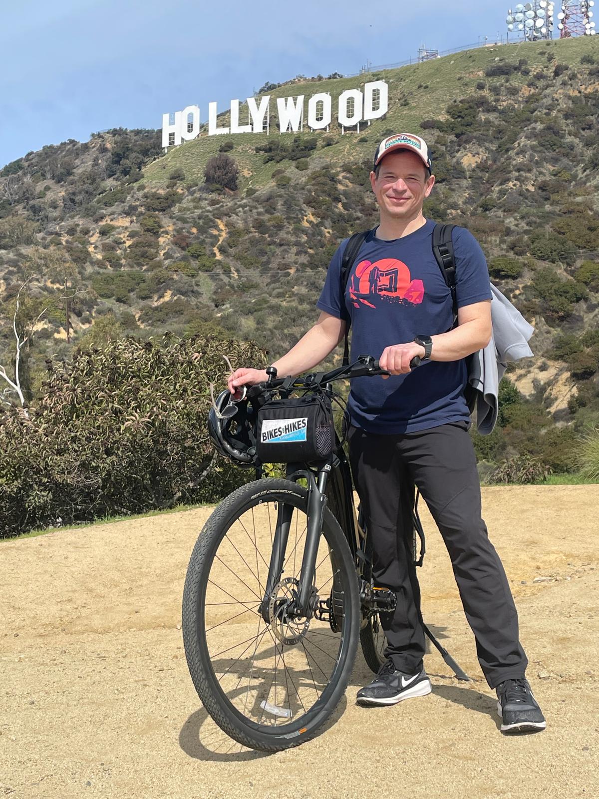 A man stands in front of the Hollywood Sign with an E-bike