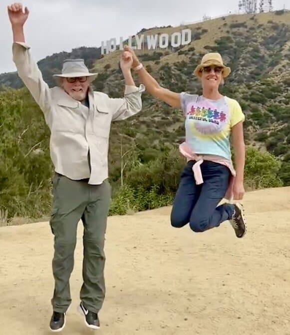 A couple jumps in front of the Hollywood Sign on the Hollywood Sign Tour