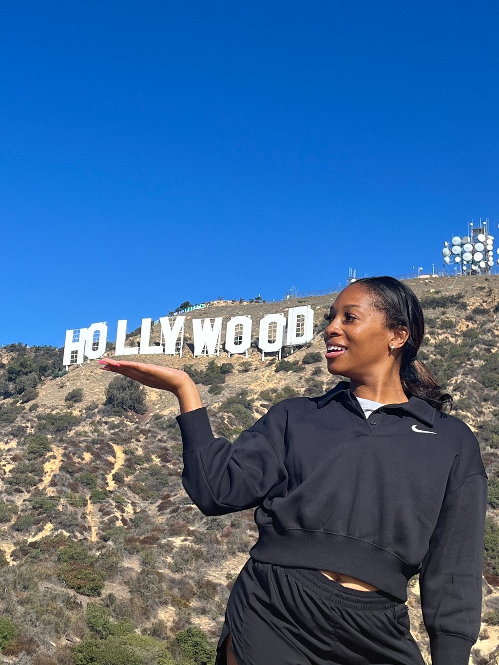 A woman appears to hold the Hollywood Sign in the palm of her hands on the Hollywood Sign Tour
