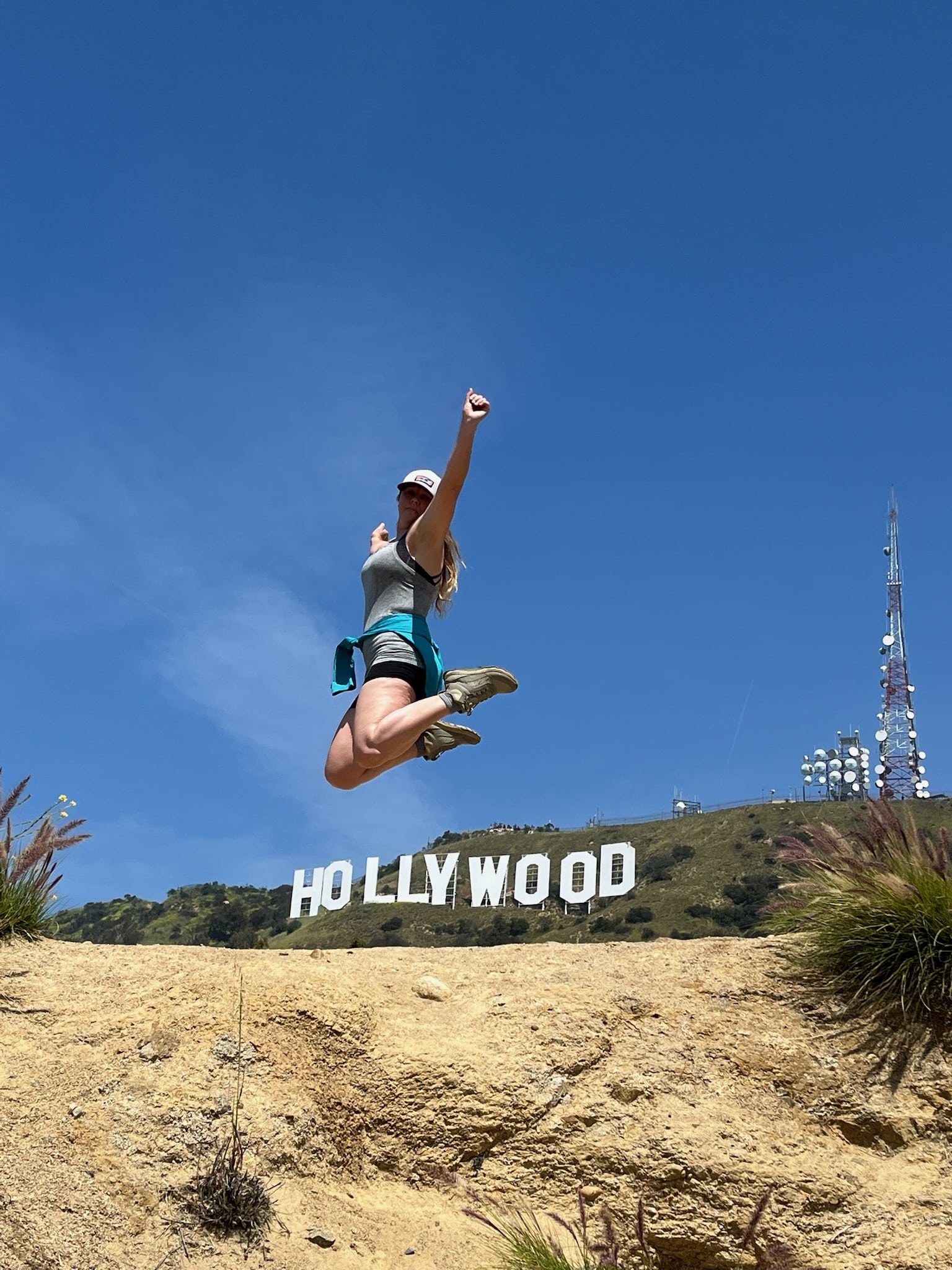 A woman jumps up over the Hollywood Sign in a pose on the Hollywood Sign Tour