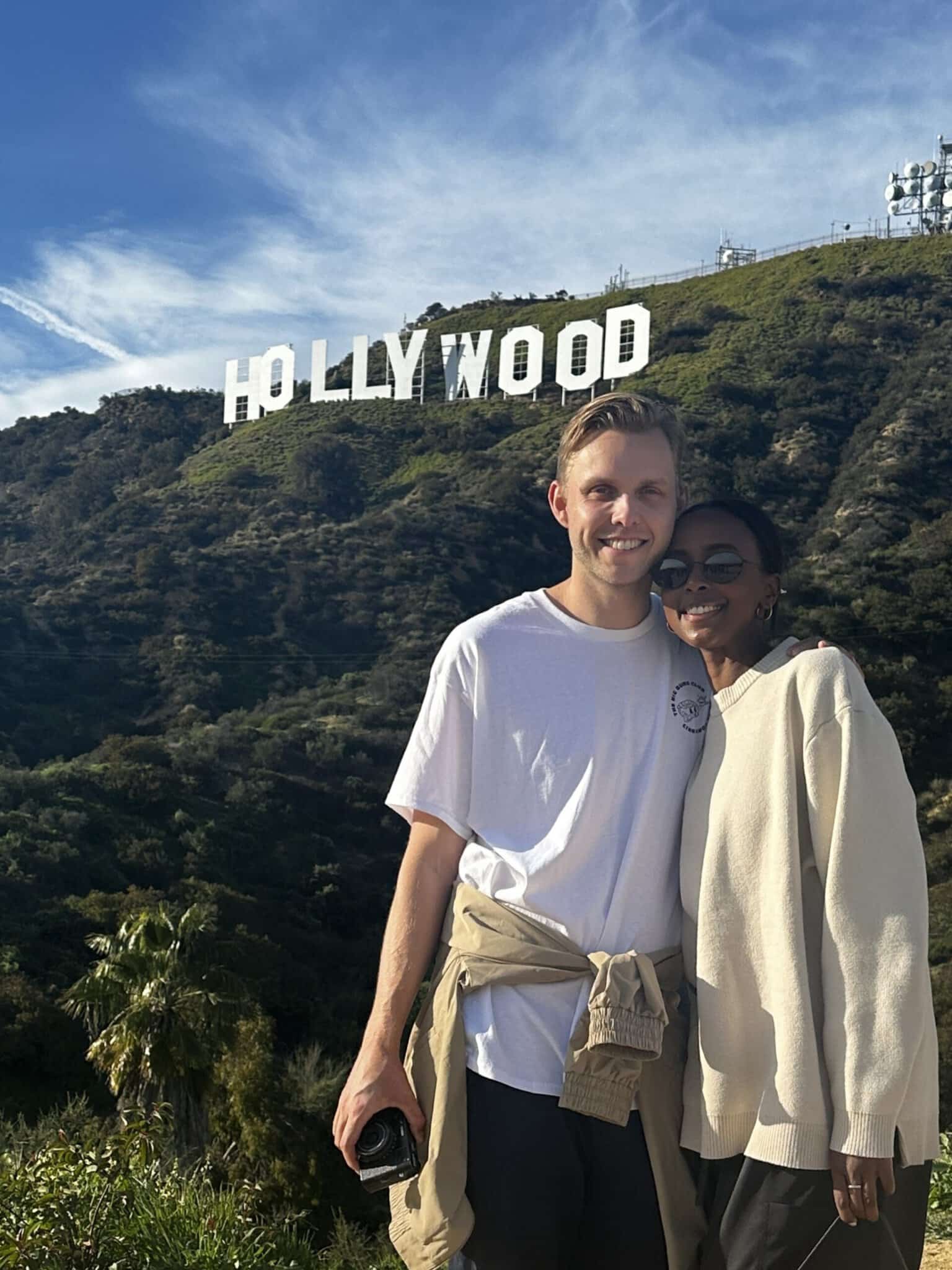 A cute couple poses in front of the Hollywood Sign on the Hollywood Sign Tour