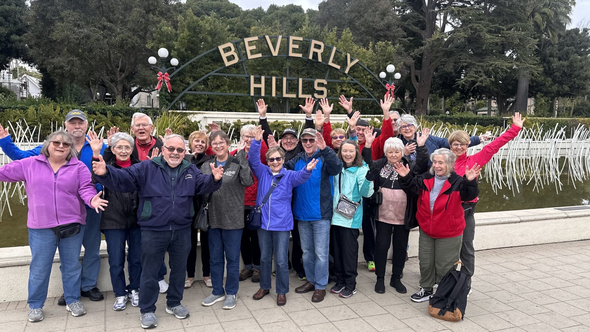 A group of guests in front of the Beverly Hills Sign with their hands up