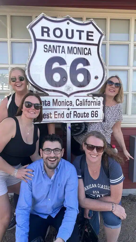 Guests pose with the Route 66 sign in Santa Monica on the Santa Monica and venice beach bike tour