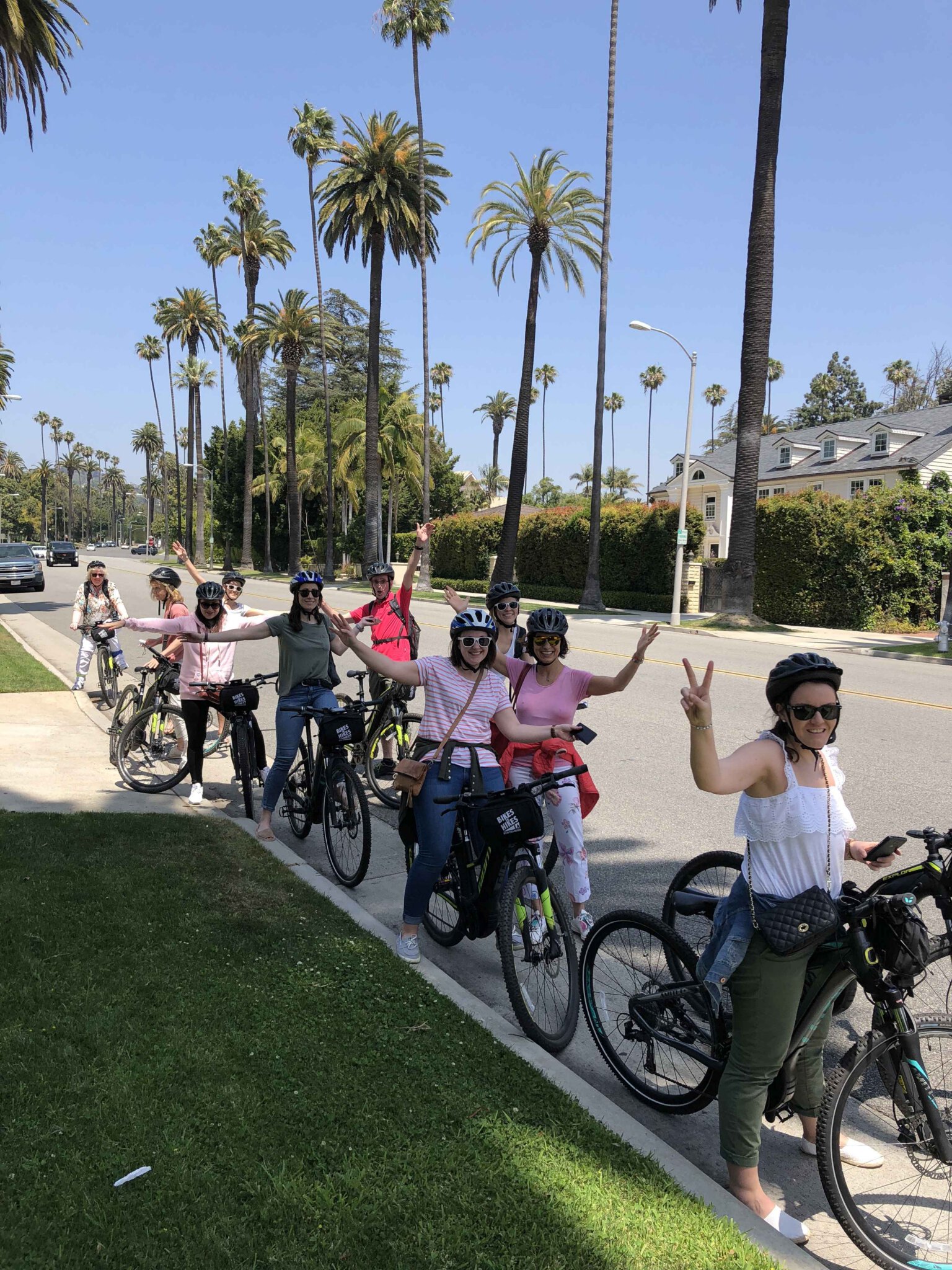 Guests smile and pose on bikes on a west hollywood street
