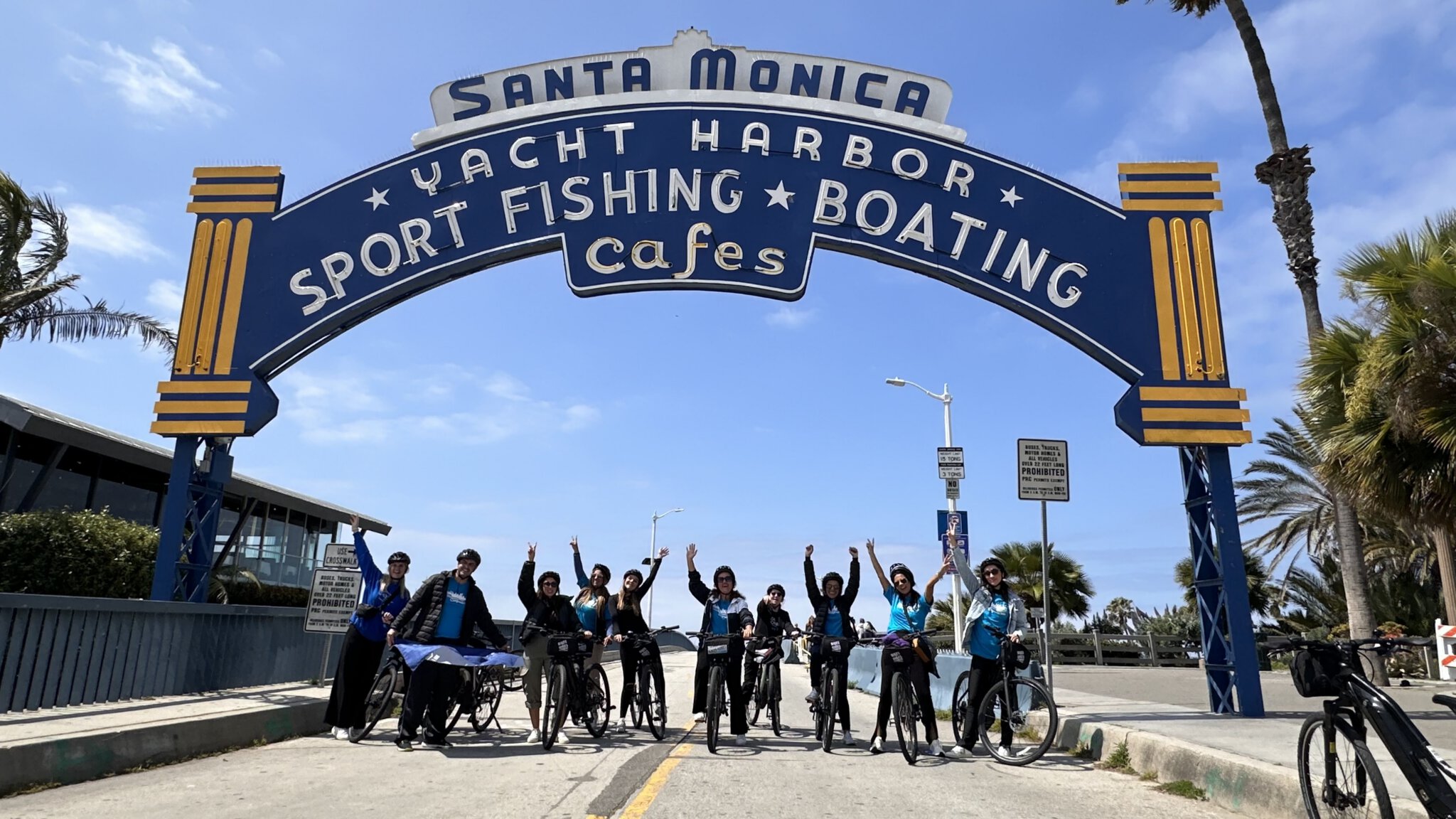 Guests underneath the Santa Monica Pier Sign on the Santa Monica and Venice Beach Bike Tour