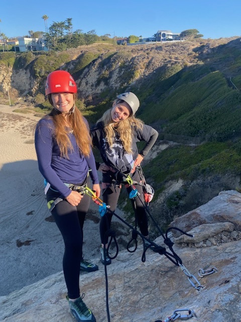 Two girls smile and pose during a rock climbing experience