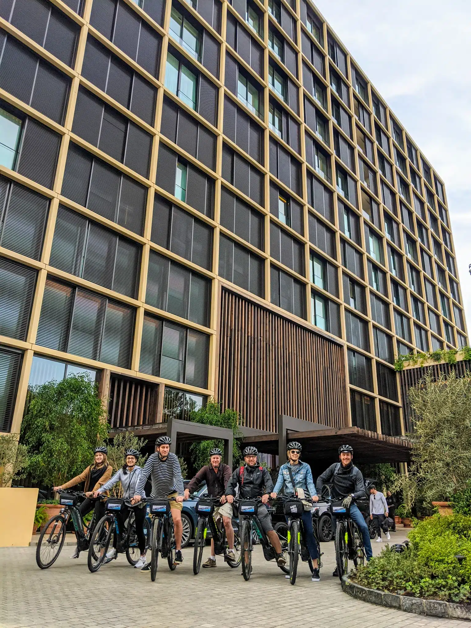 Guests smiling on bikes in front of a hotel on the West Hollywood Bike Tour