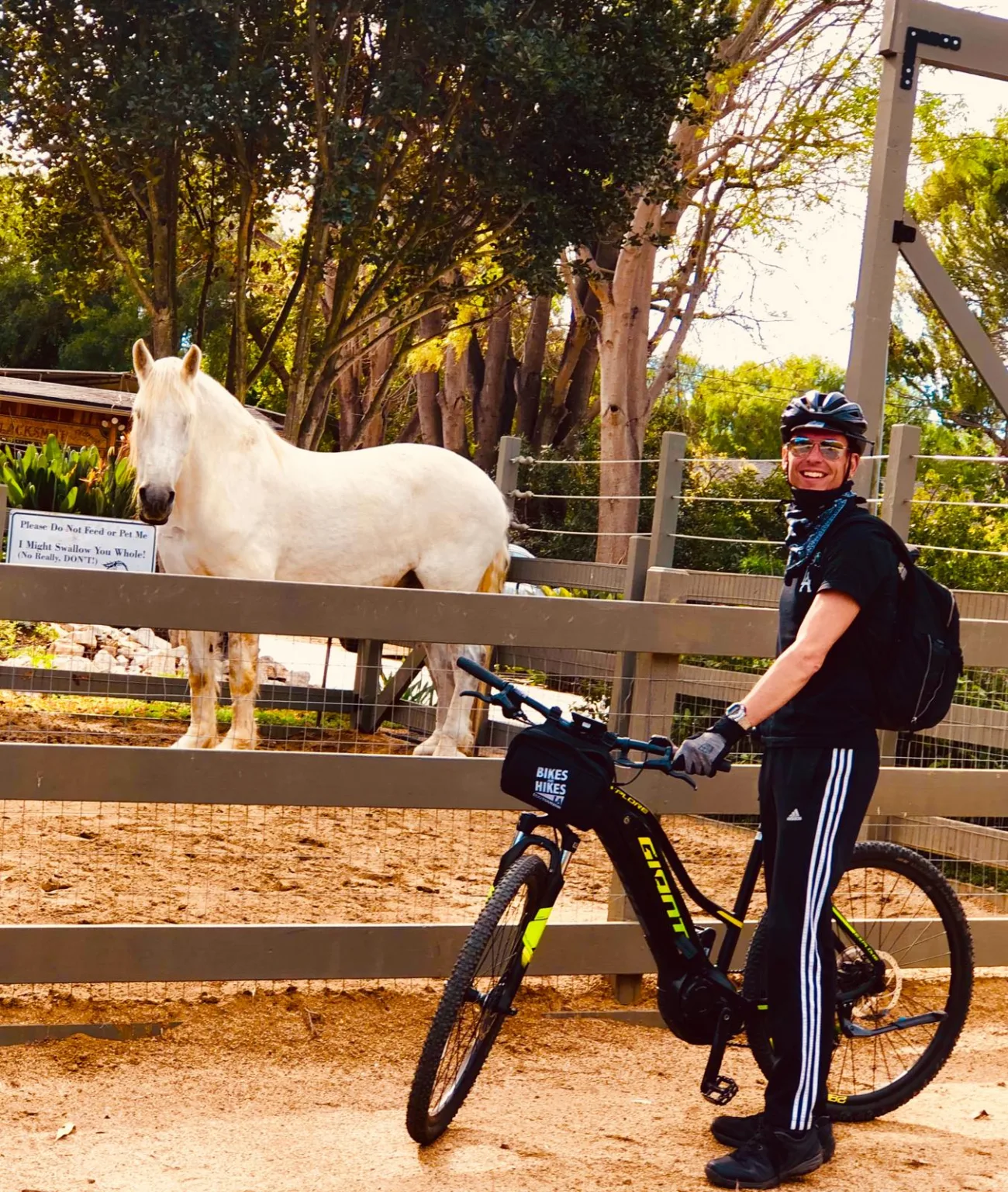 A man poses with a cute white horse while mountain biking in Palos Verdes.