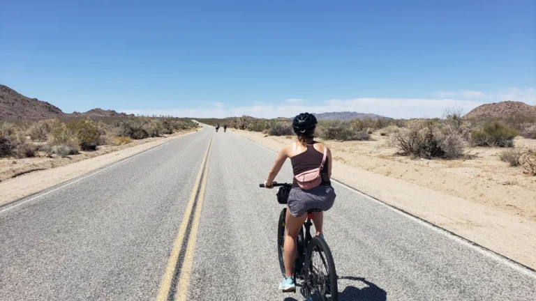 A woman rides down a desert road on an e bike on the Joshua Tree Bike Tour