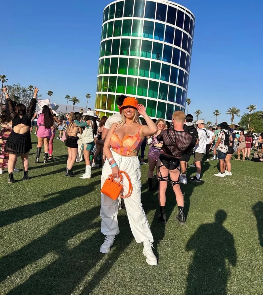 A girl stands on the Coachella grounds in front of an art installation