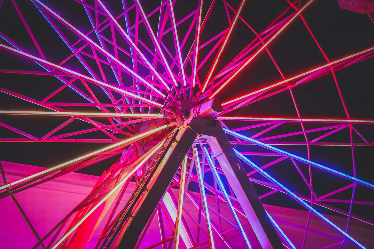 The Coachella Ferris wheel lit up in pink orange and blue at night