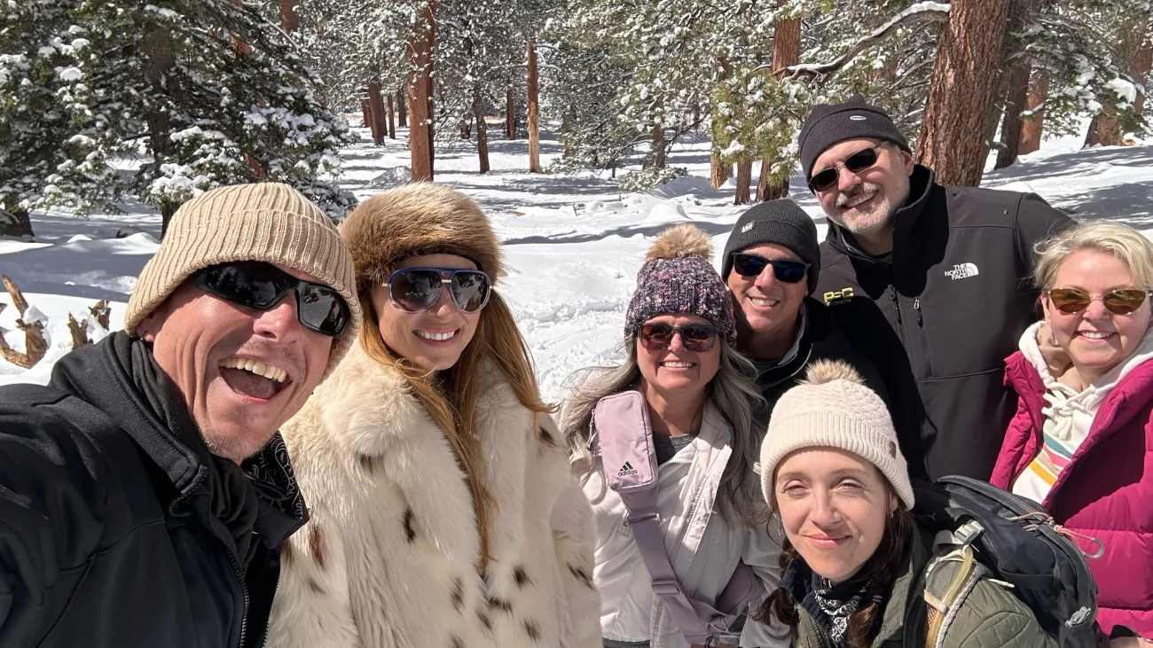 Guests smile at the camera in a snowy scene at the top of Mt. Jacinto
