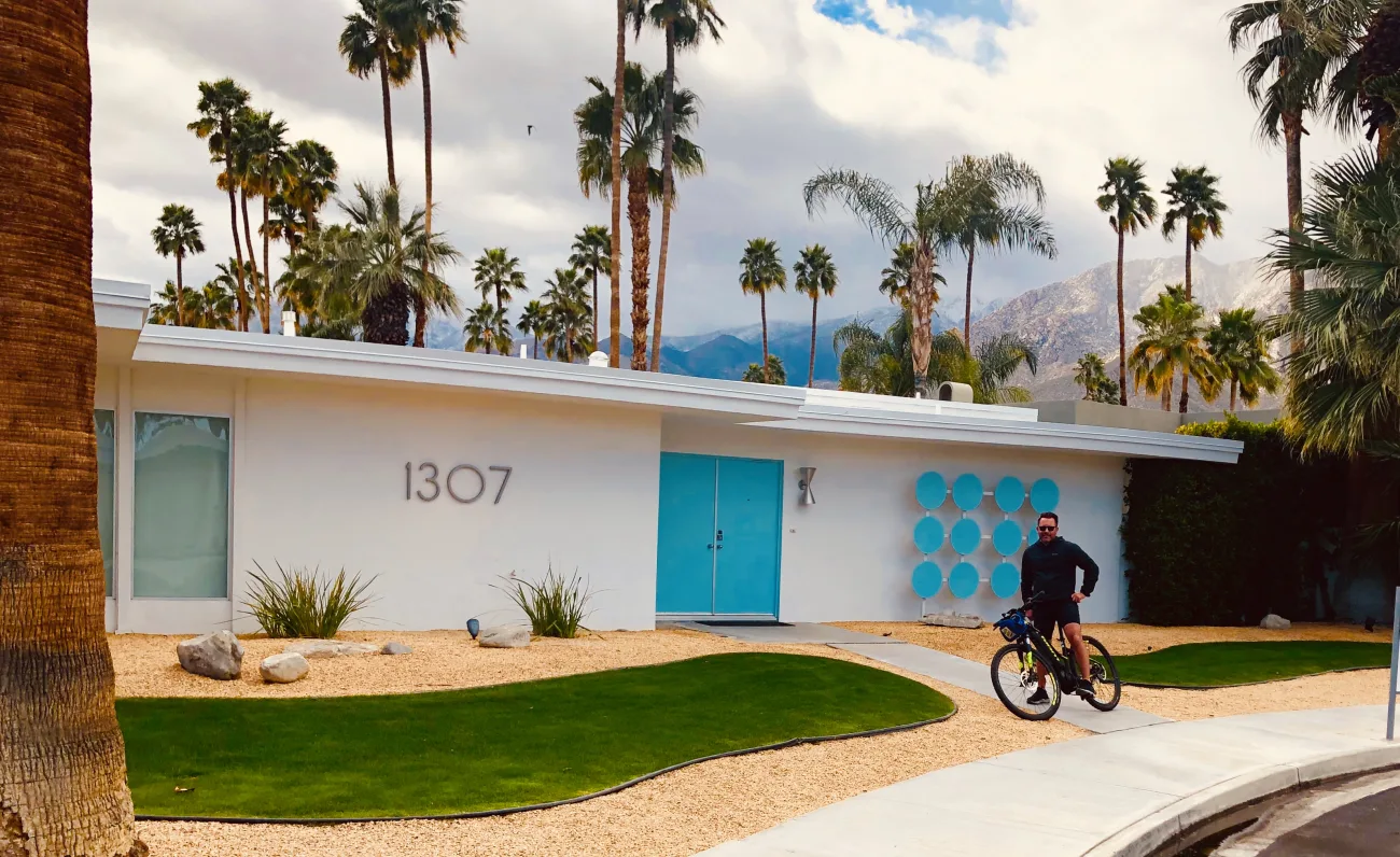 Man on a bike in front of a mid century modern home in Palm Springs