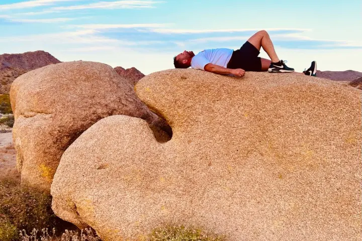 A man lays on a rock in Joshua Tree on the Joshua Tree Hiking Tour