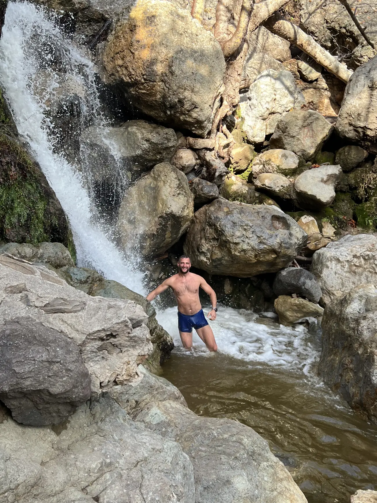 A guest bathes in a waterfall on the Solstice Canyon Hike