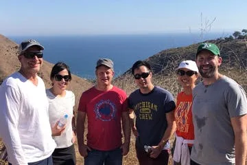 A group smiles with the ocean in the background