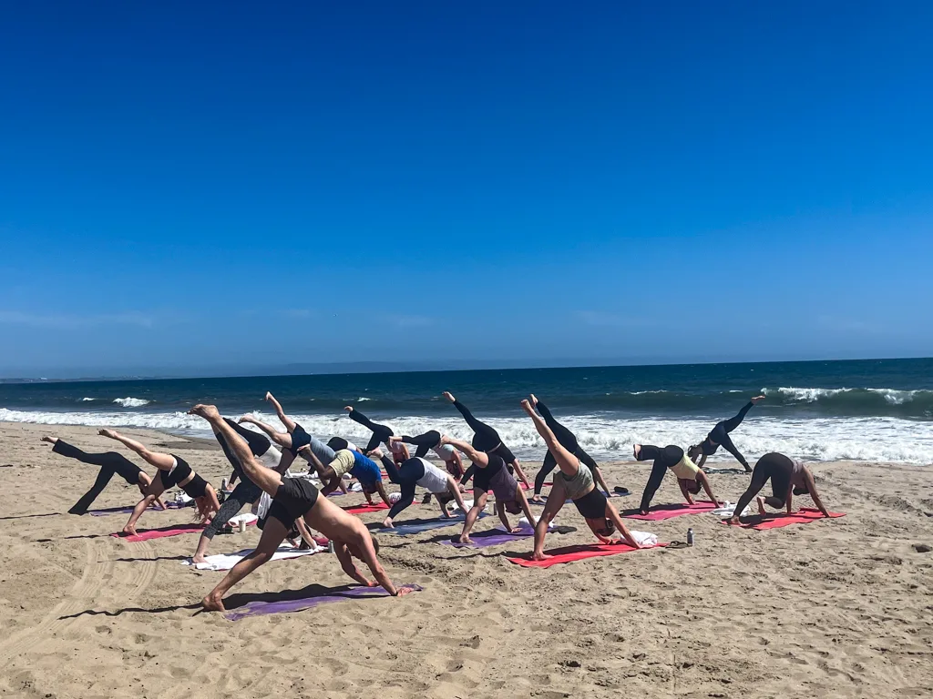 Clients pose for yoga on the beach