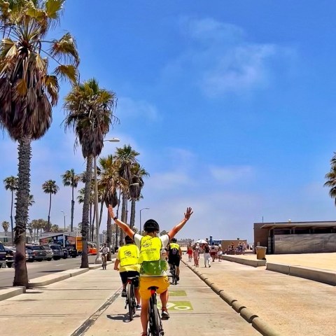 a group of people riding bikes down the beach in santa monica
