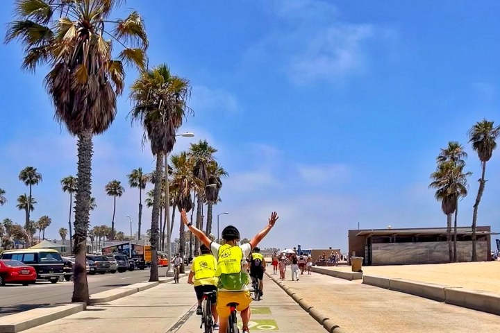 a group of people riding bikes down the beach in santa monica