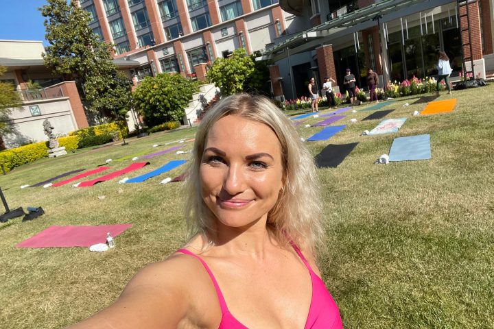 a blonde woman poses in front of a group of yoga mats in westlake