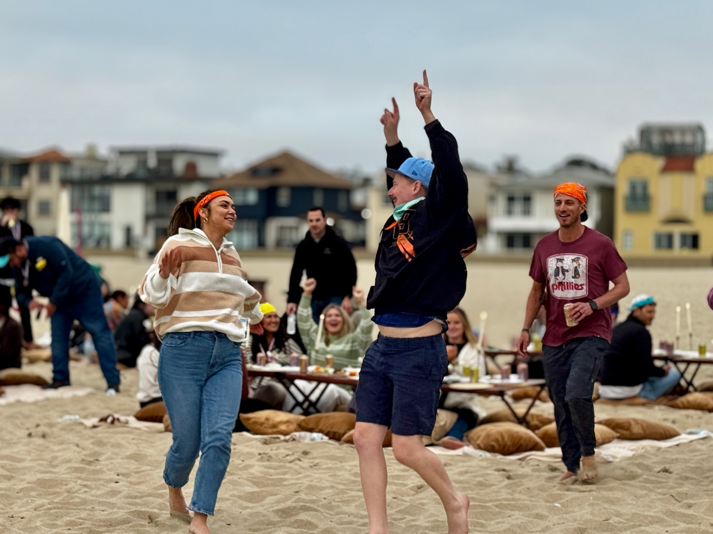 a group of people playing frisbee on a sandy beach