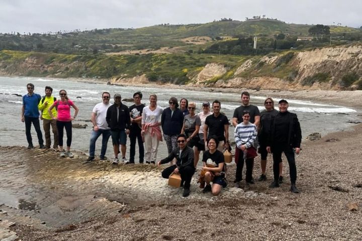 a group of people standing on top of a sandy beach on a group walking tour