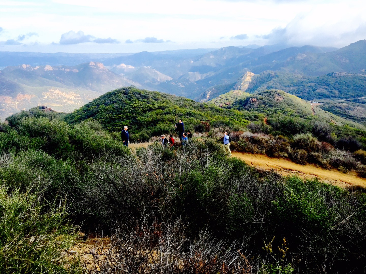 A group hiking through a path on Sandy Peak