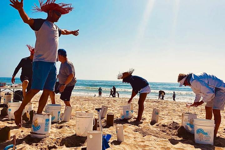 a group of people on a beach building sand castles on a team building activity