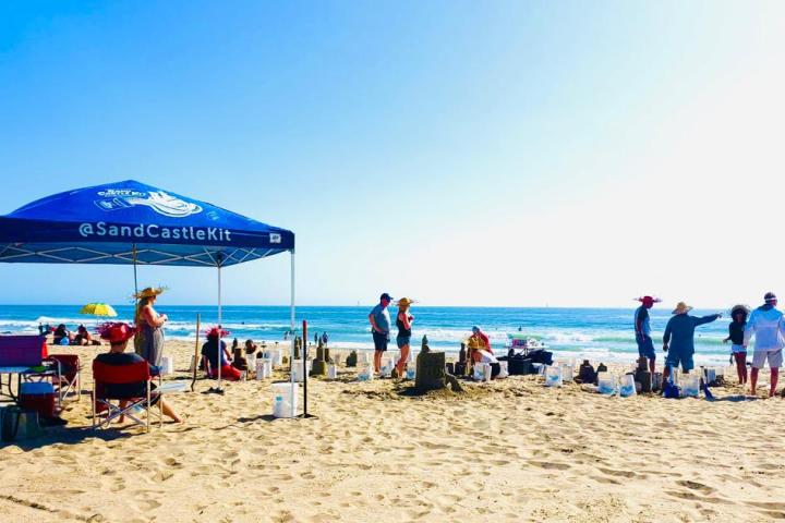 a group of people on a beach building sand castles on a group team building experience