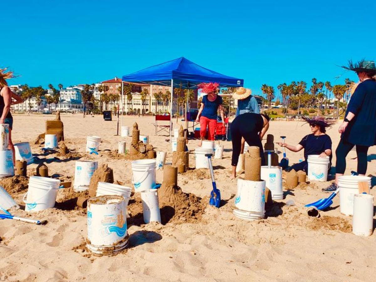 a group of people sitting at a beach building sand castles on a vip tour