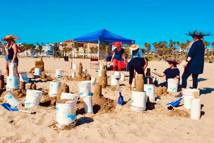 a group of people sitting at a beach building sand castles on a vip tour