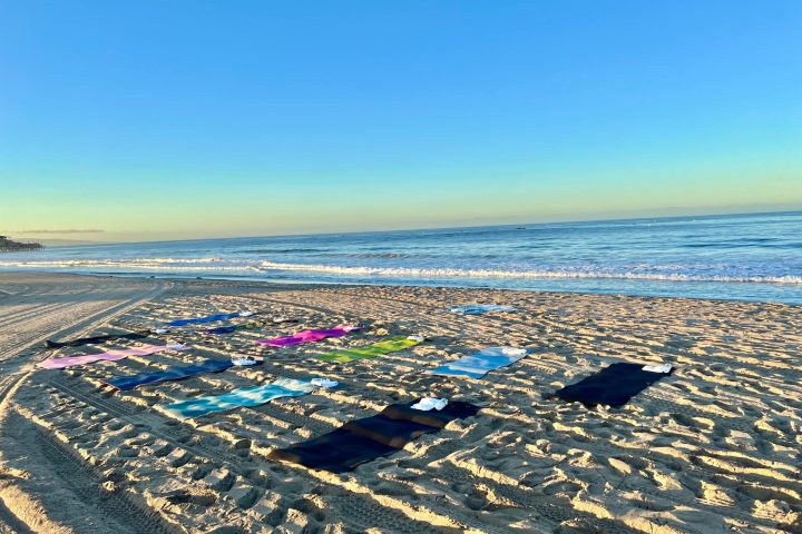 a group of people doing beach yoga at a team building event