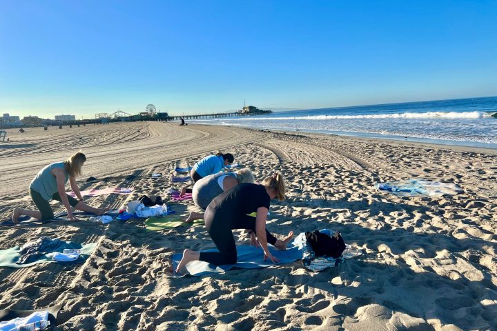 a group of people doing beach yoga at an outdoor team building event