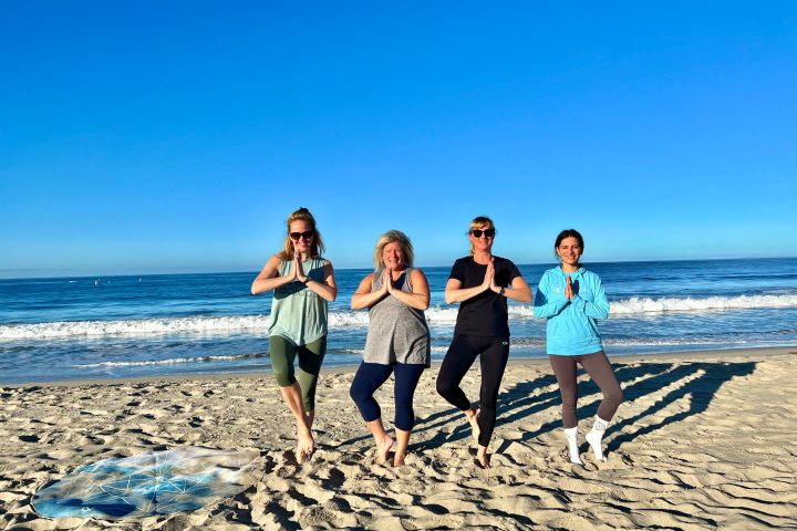 a group of people doing corporate team building yoga on a beach