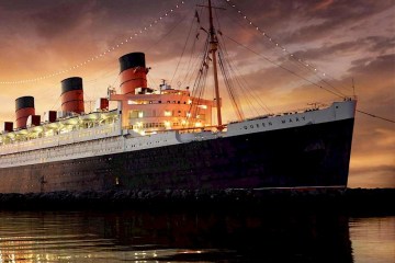 a large ship in a body of water with RMS Queen Mary in the background