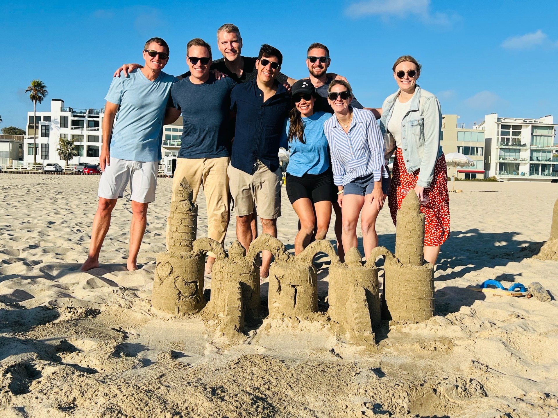 a group of people standing by a sandcastle from a group sand castle building lesson