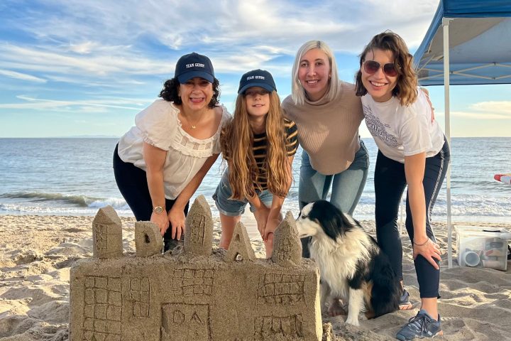 a group of people standing on a beach posing for the camera