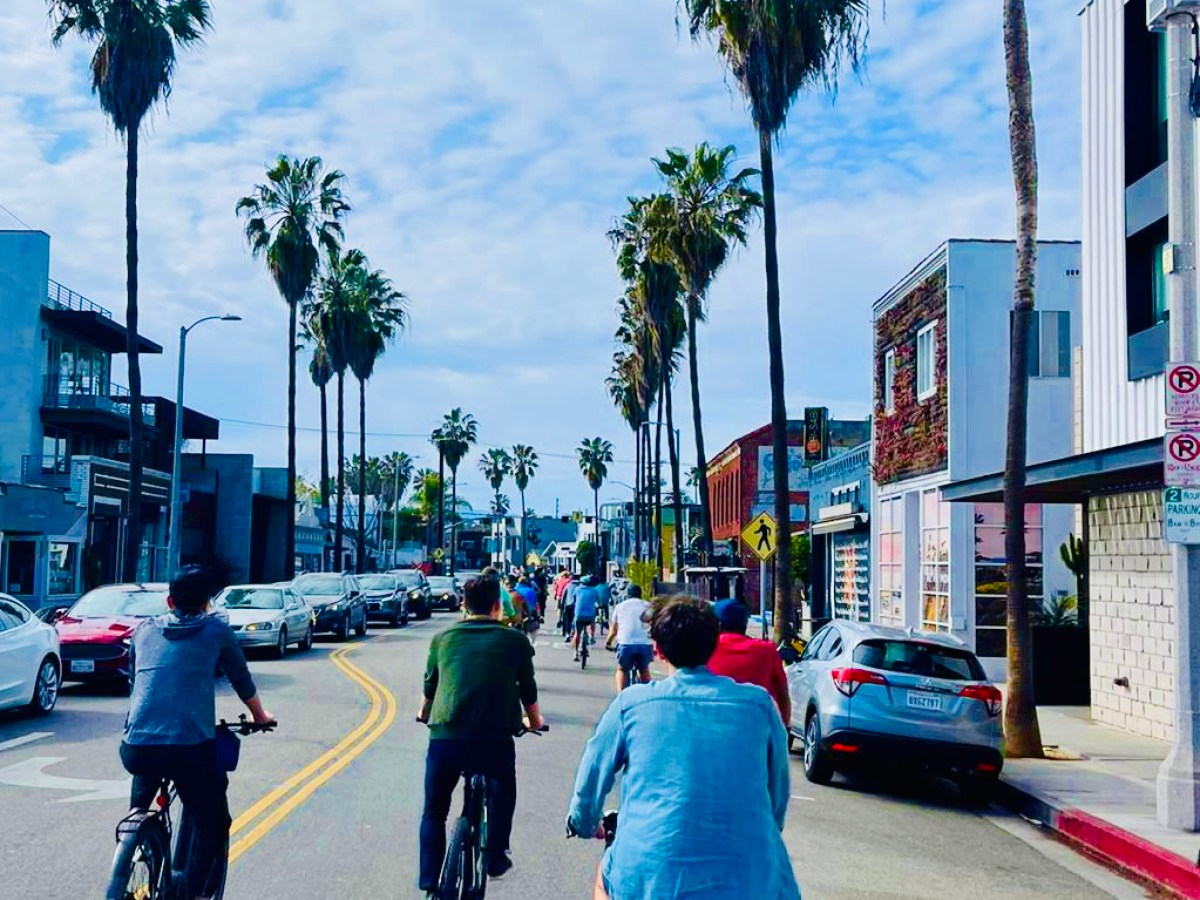 a group of people riding bikes down a street in venice ca