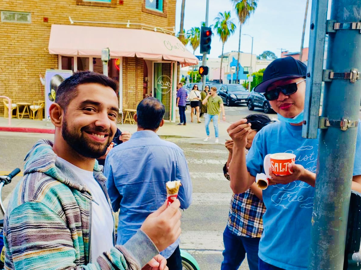 a group of people standing on the street eating ice cream in venice california