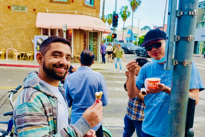 a group of people standing on the street eating ice cream in venice california