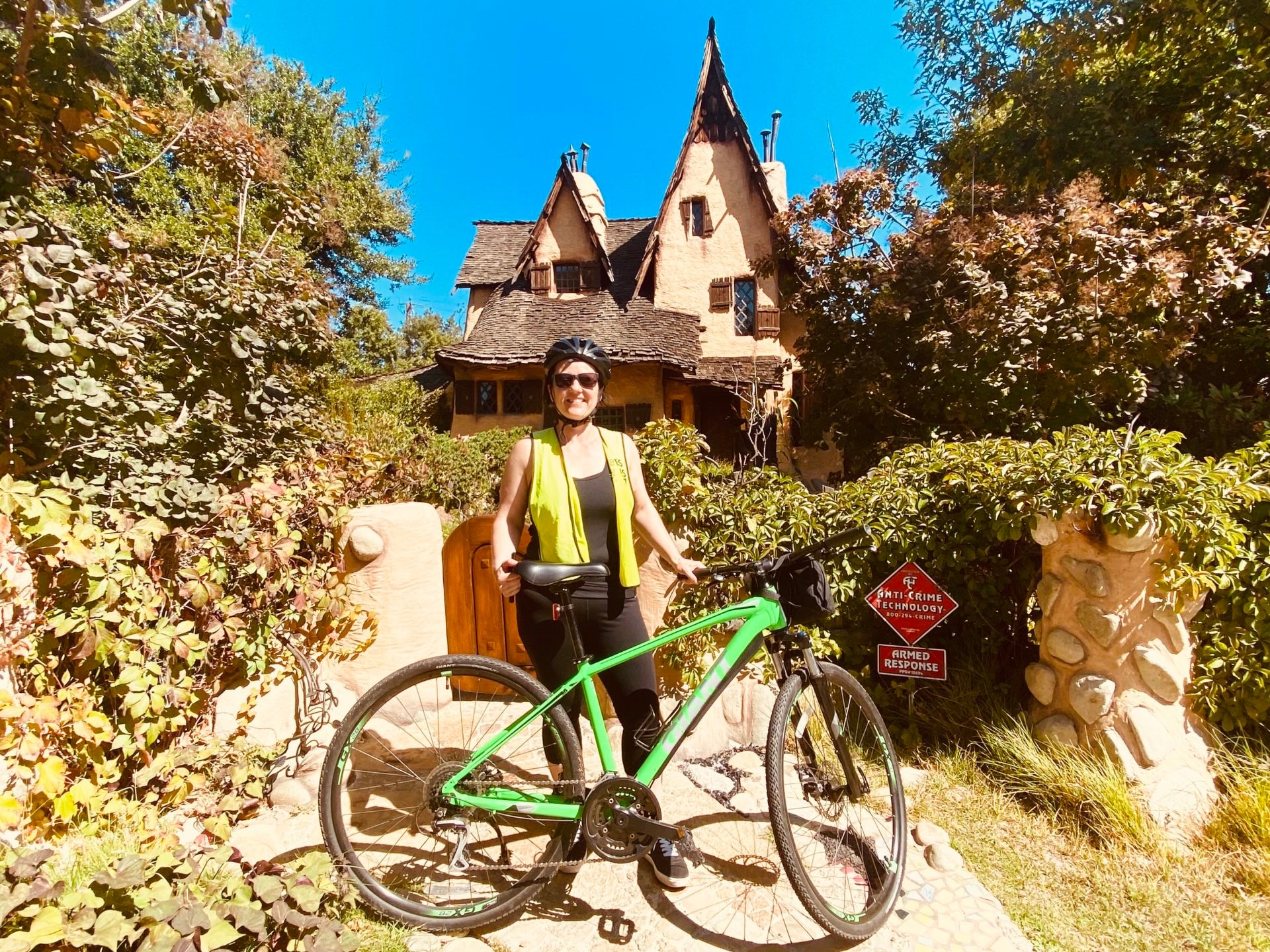 a person standing next to a bicycle outside of a celebrity home in beverly hills