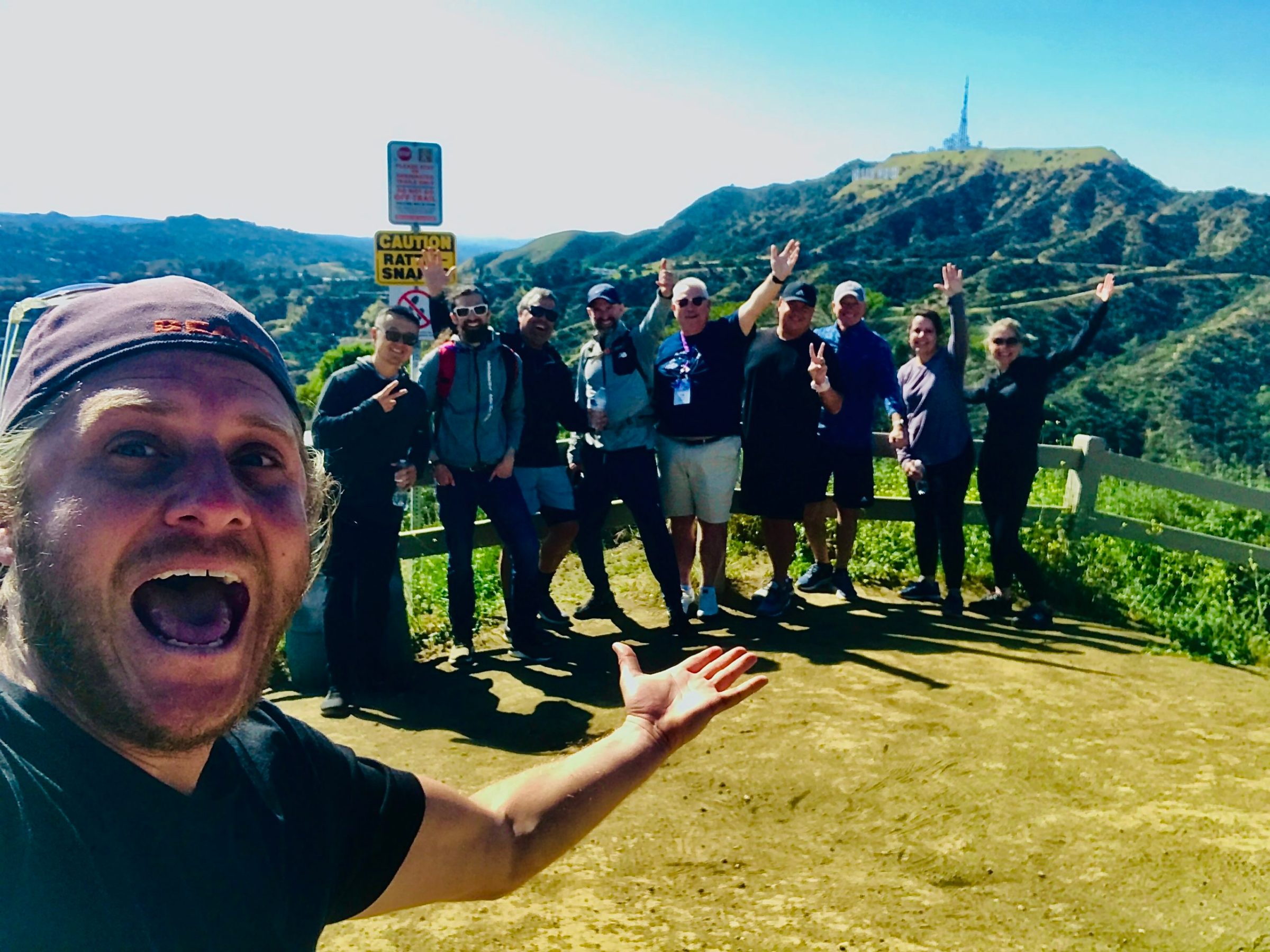 a group of people standing by the hollywood sign on a hollywood hills hike tour