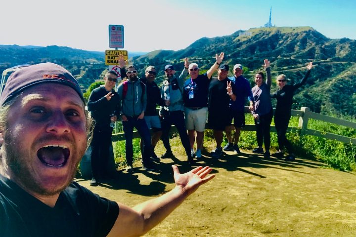 a group of people standing by the hollywood sign on a hollywood hills hike tour